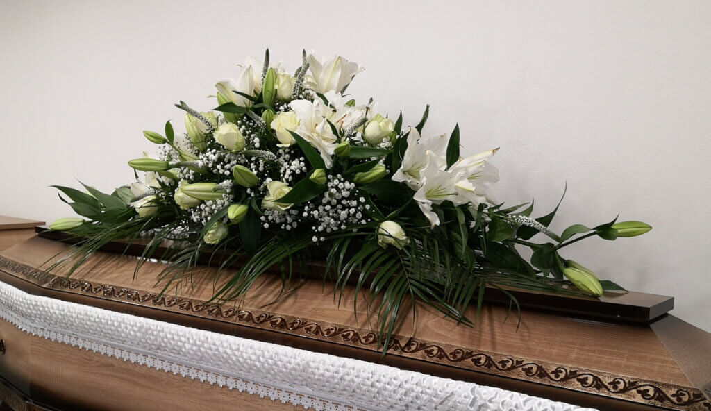 Pohrebná výzdoba s bielymi ľaliami a zelenými listami.
